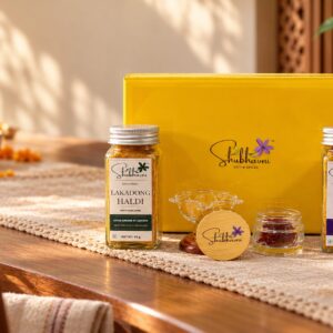 Shubhavni Celebration Box with Lakadong haldi, Swarna, kesar and a glass diya on a festive table