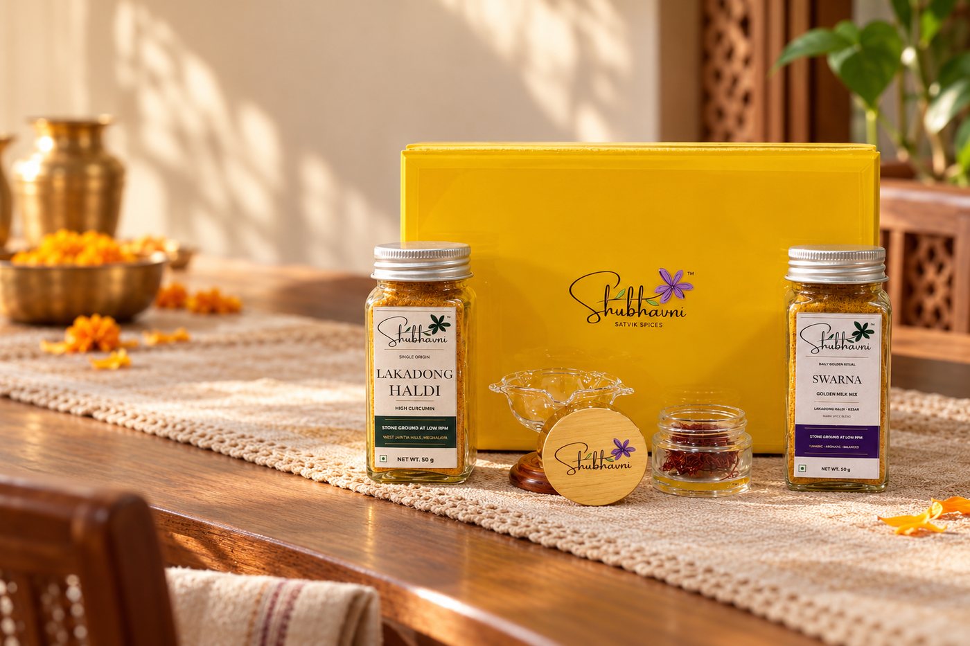 Shubhavni Celebration Box with Lakadong haldi, Swarna, kesar and a glass diya on a festive table