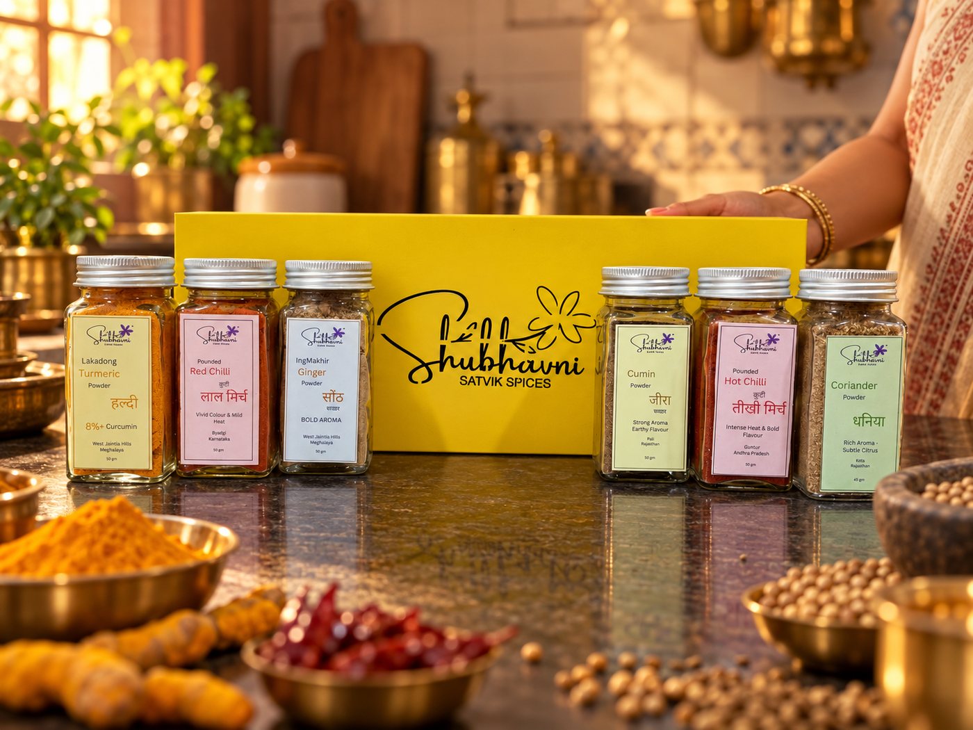 Shubhavni Stone Ground Spices Box set out in a home kitchen with whole haldi, chillies and dhaniya